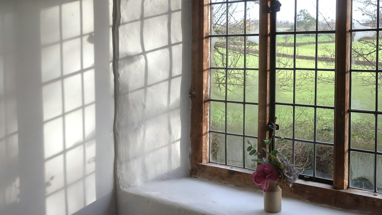 A small vase of flowers on a sunny window sill